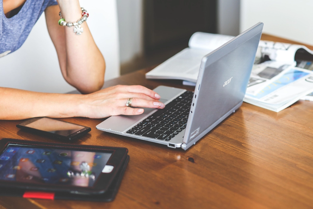 Person working on laptop with tablet and phone