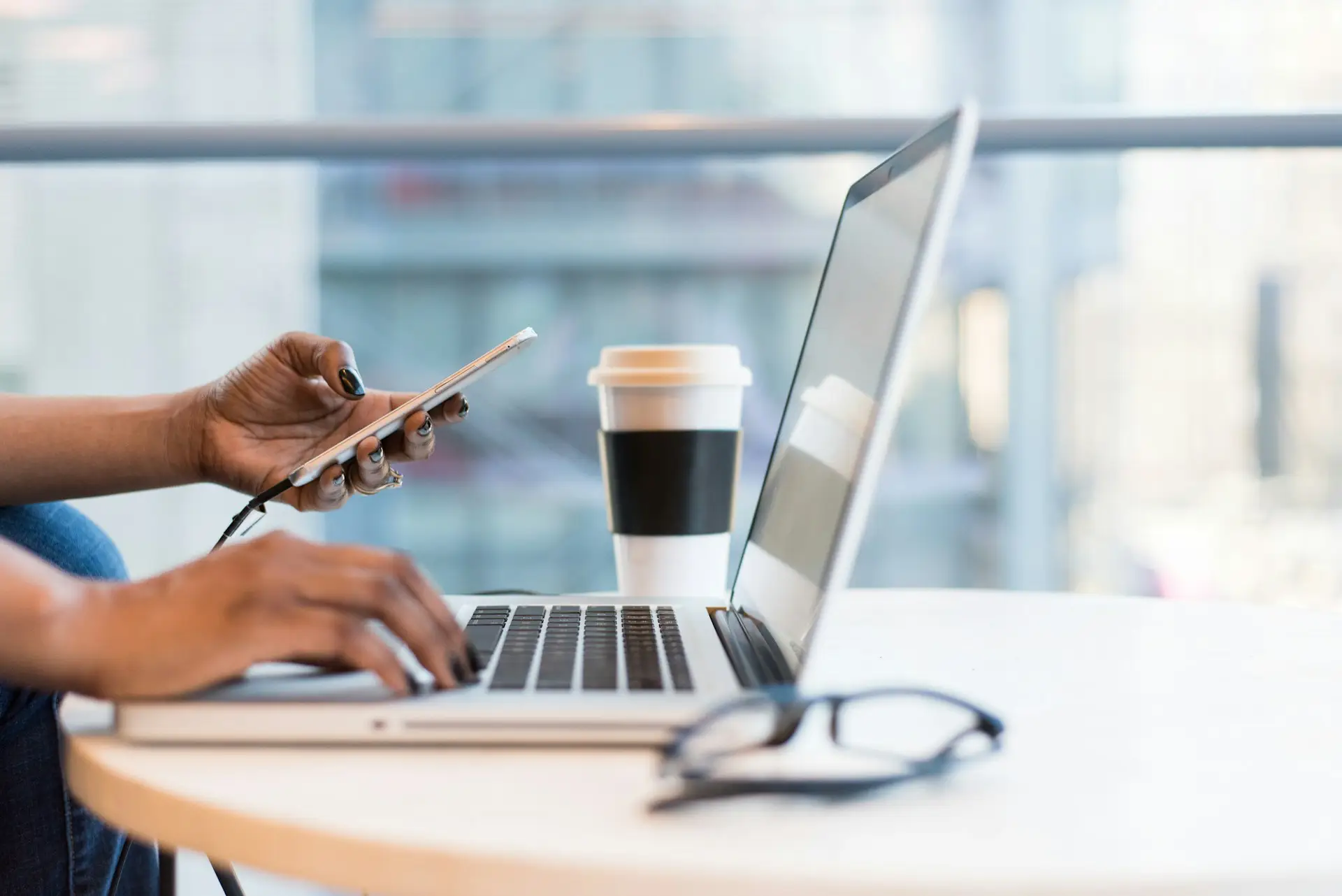 Person using laptop and phone at coffee shop